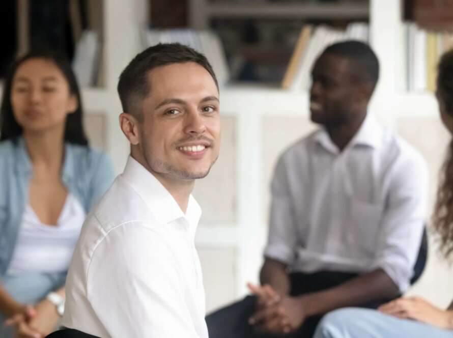 happy man looking at the camera sitting in group therapy