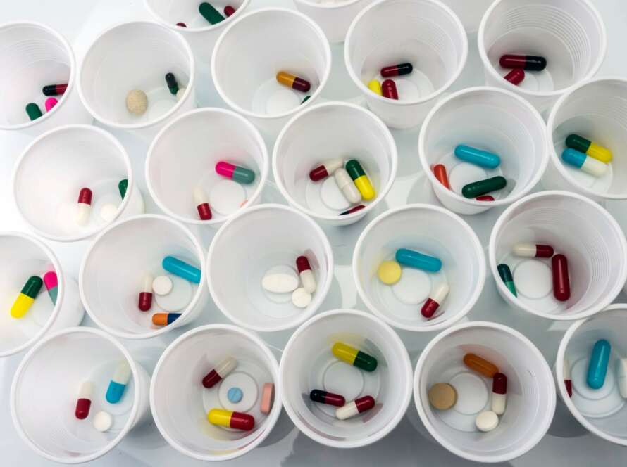 top-down image of various medications and pills in cups