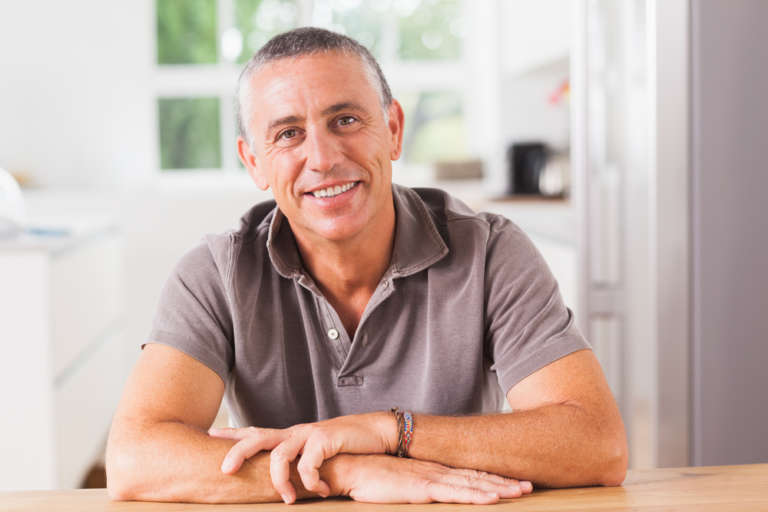 happy man sitting at table in kitchen